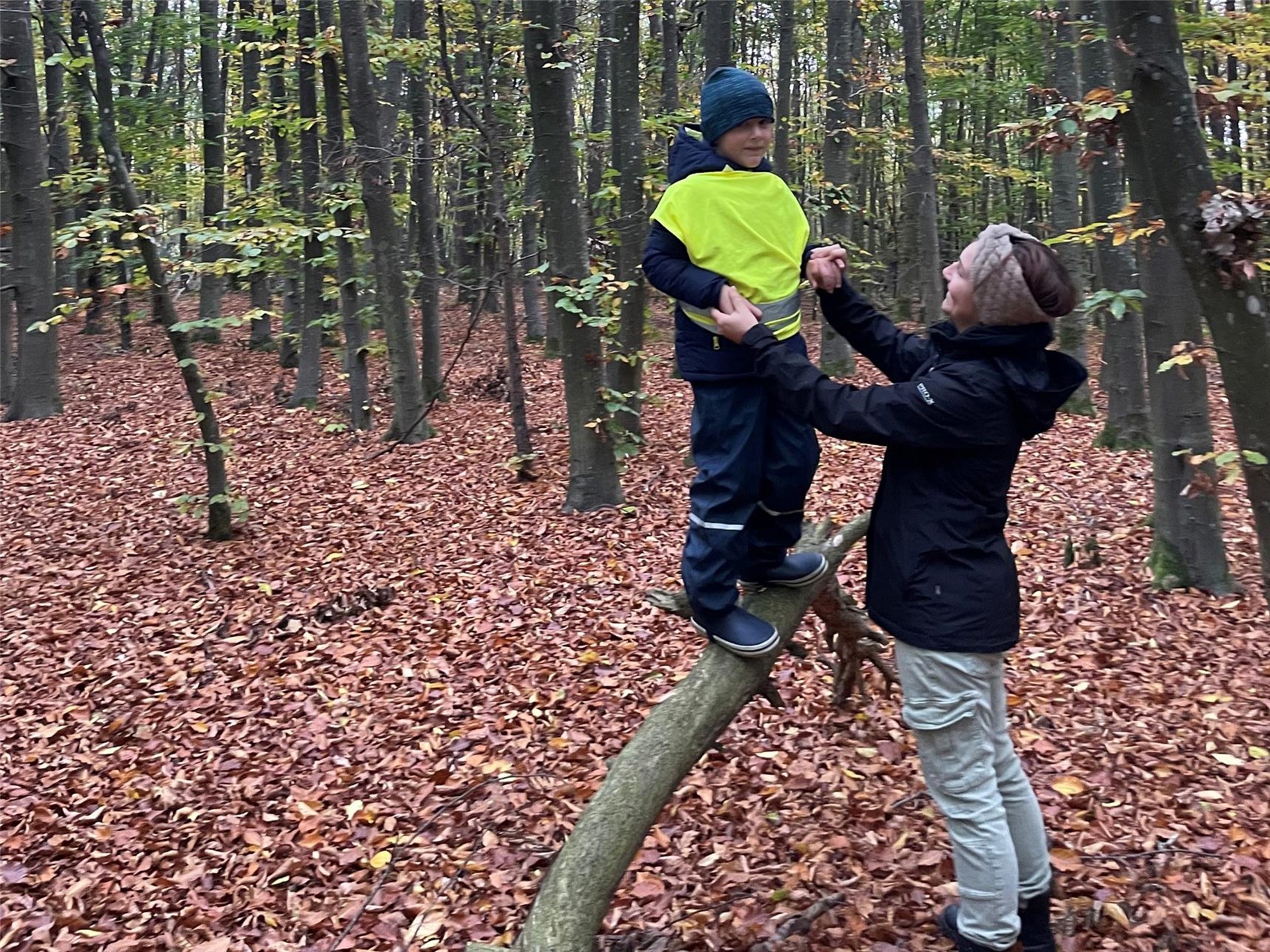 Wald: Frau hält Kind auf Baumstamm fest